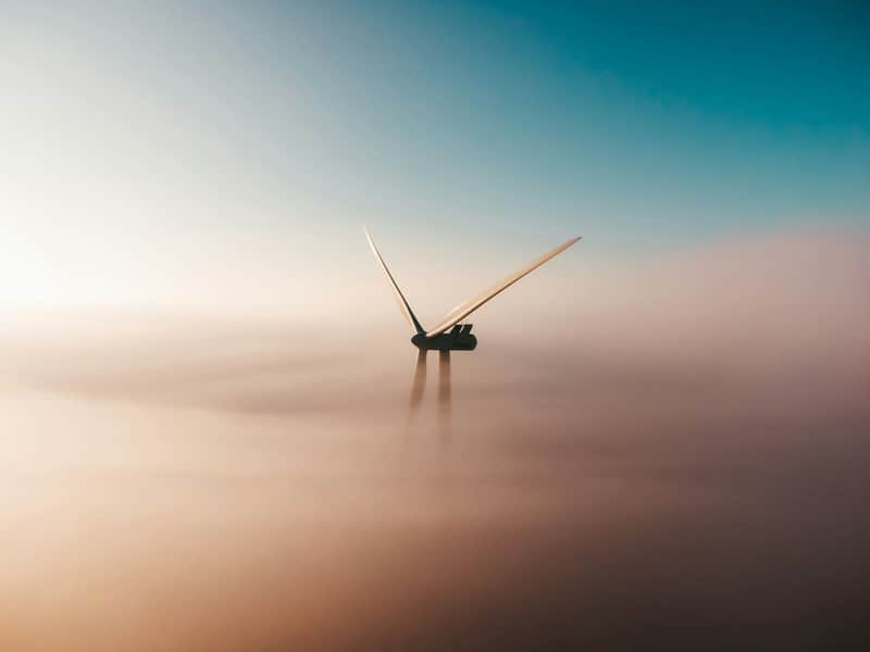An offshore wind turbine rising through fog