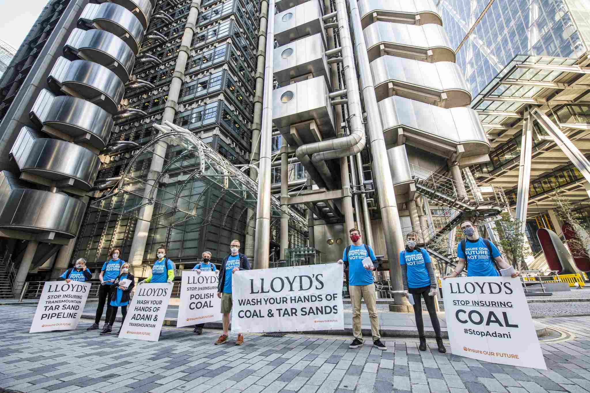 Activists stand with signs outside of Lloyd's calling for an end to fossil fuel insuring